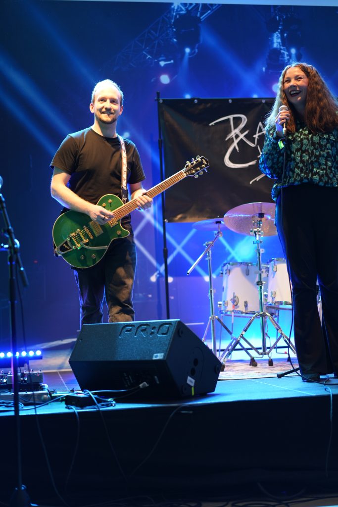 Fotografin Bonn: Konzertfotografie vom Gitarristen und der Sängerin auf der beleuchteten Bühne