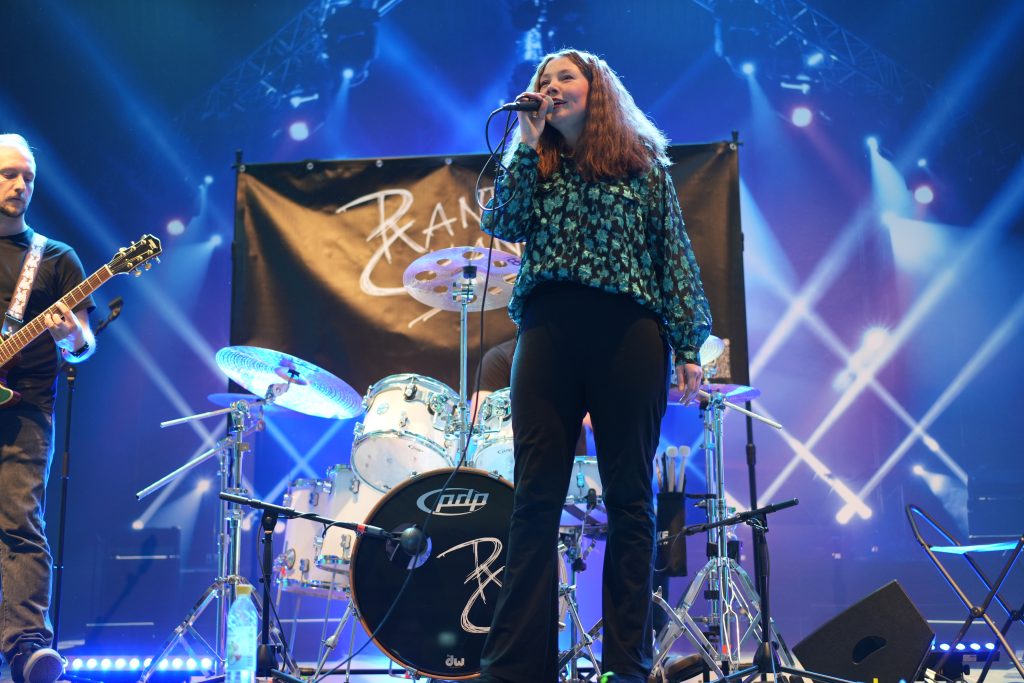 Professionelle Eventfotografin aus Bonn fotografiert Live-Konzert auf der Bühne mit Sängerin und Schlagzeug