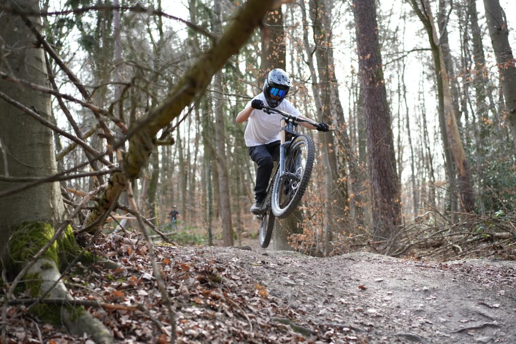 Professionelle Sportfotografin Bonn: Mountainbiker beim Wheelie im Wald | Bilder für E-Commerce und Social Media