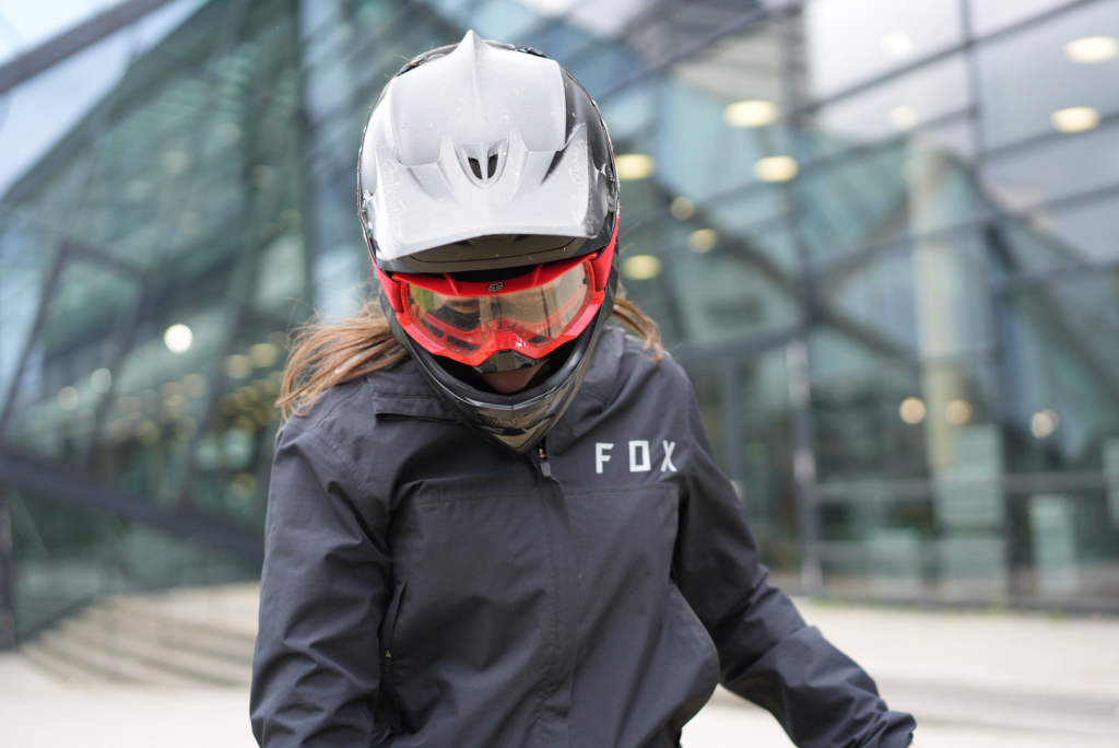 Nahaufnahme MTB-Fahrerin mit roter Goggle und schwarzer Fox-Jacke, dynamisch fotografiert von Malin Kalwa in Bonn