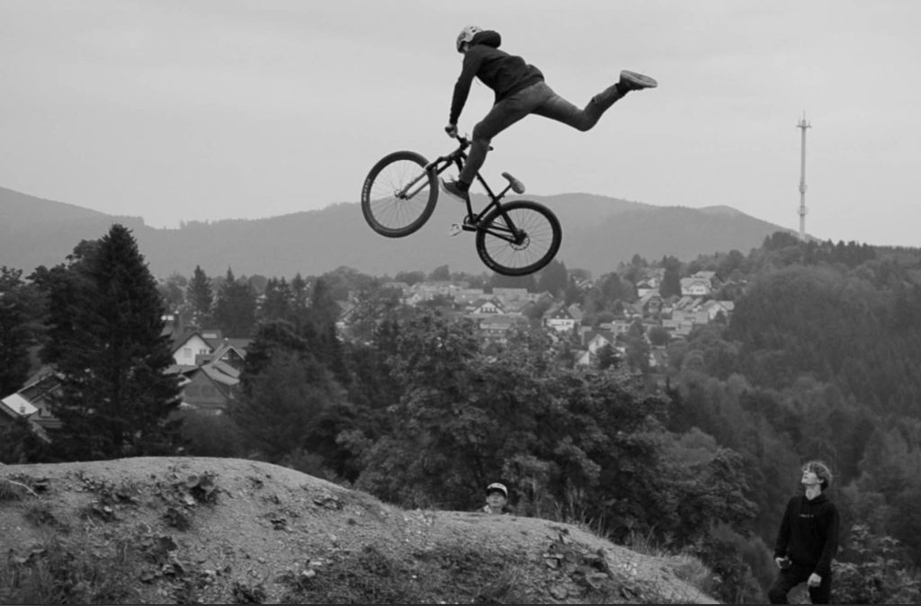 Eventreportage Mountainbike: Schwarz-Weiß-Foto eines Bikers bei einem hohen Sprung über die Skyline | Fotografin Bonn