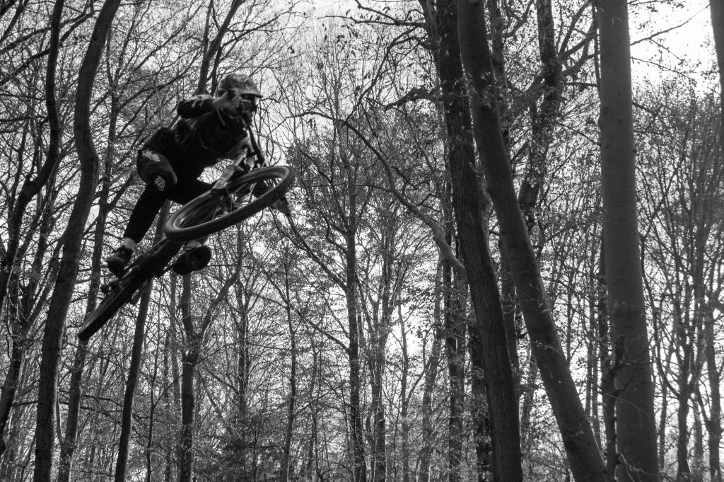 Social Media Content: Schwarz-Weiß-Foto eines Mountainbikers beim Sprung im Wald | Fotografin Bonn für Sportmarketing