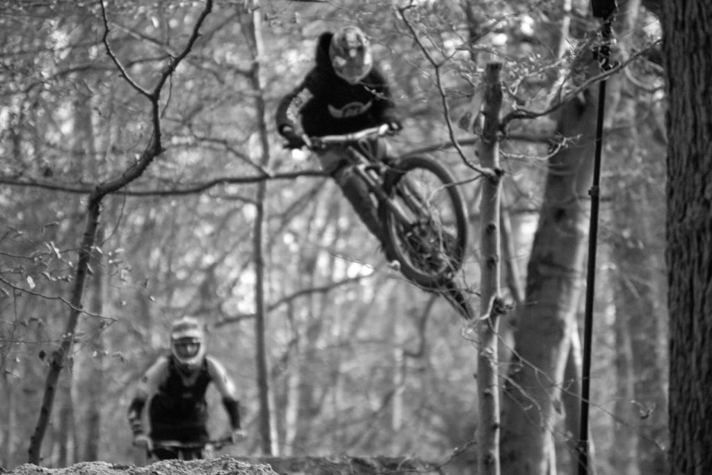 Eventfotografie Nutbush Köln: Mountainbiker beim Sprung im Wald | Schwarz-Weiß-Aufnahme von Fotografin Bonn