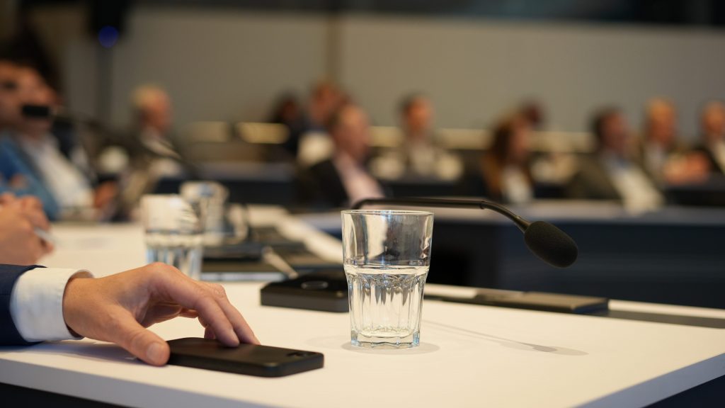 Nahaufnahme Hand auf Smartphone an Konferenztisch Mikrofon Wasserglas Wissenschaftszentrum Bonn Fotografin kamaka