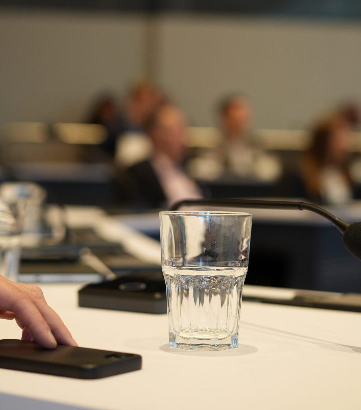 Nahaufnahme Hand auf Smartphone an Konferenztisch Mikrofon Wasserglas Wissenschaftszentrum Bonn Fotografin kamaka