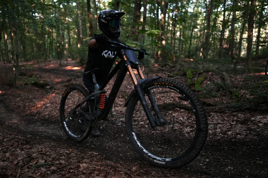 MTB-Fahrer im Kali Protectives Shirt balanciert auf Hinterrad (Manual) auf Waldtrail, Action-Foto von Bonner Fotografin Malin Kalwa