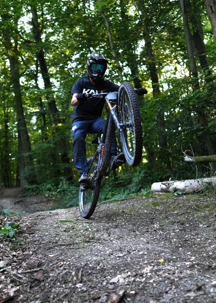 Influencer mit Downhill-Bike im Manual/Wheelie auf dem Trail, geshootet für Kali Protectives von Fotografin Malin Kalwa