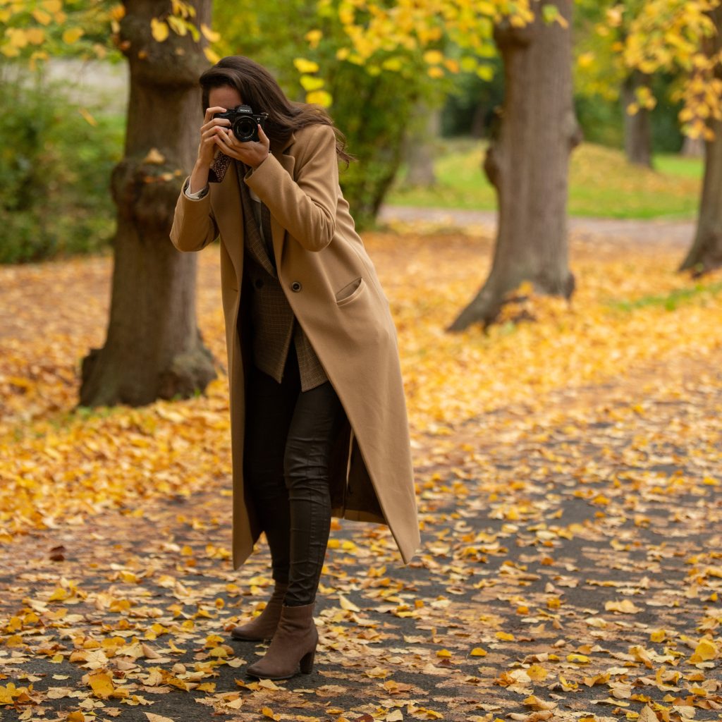 Ganzkörperansicht Fotografin Malin Kalwa Bonn in beigem Mantel fotografiert im Herbst Park in Rheinbach