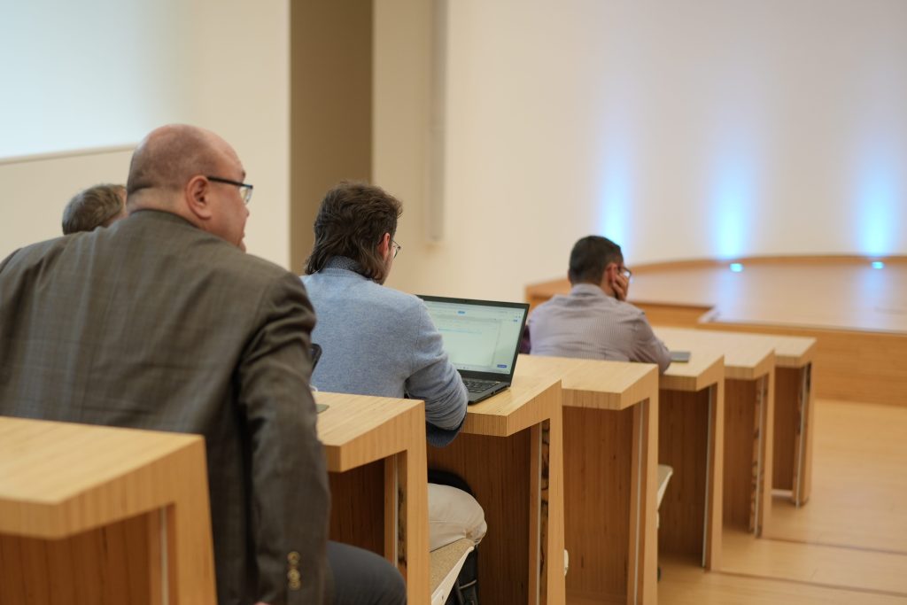 Teilnehmer im blauen Pullover arbeitet an Laptop bei Konferenz Reportagefotografie Bonn Kamaka.info