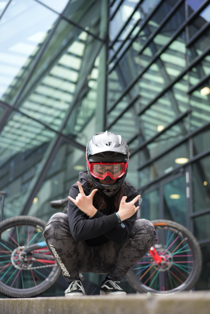 MTB-Fahrerin im coolen Style mit Helm und Brille vor moderner Architektur, perfekt in Szene gesetzt von Malin Kalwa (Bonn)